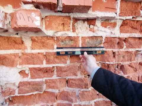 Замер кирпича линейкой на стене